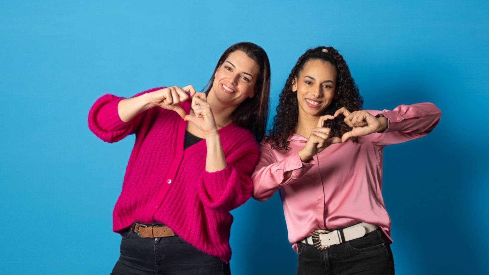 Deux jeunes femmes souriantes font des cœurs avec leurs mains