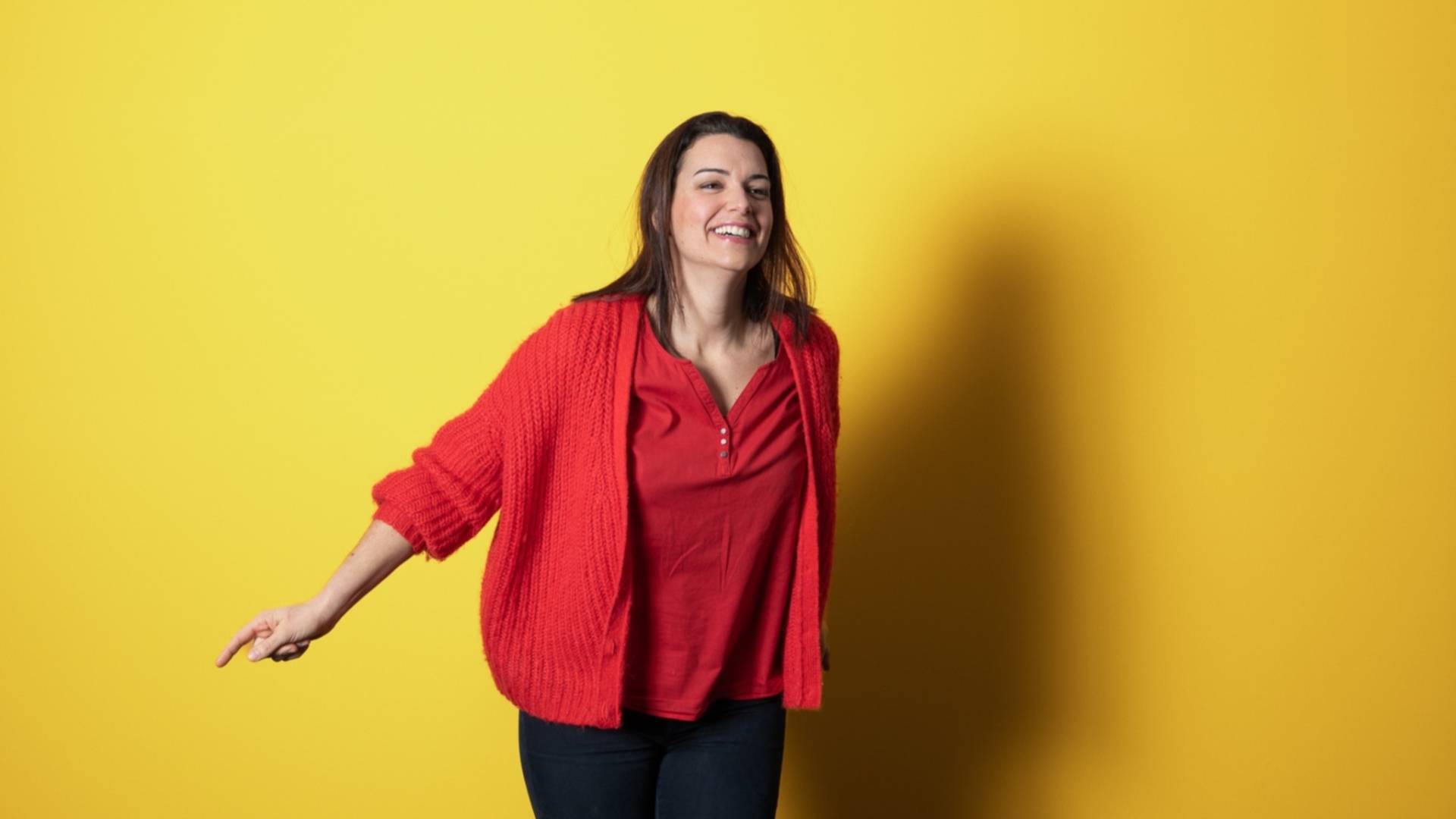 Femme souriante au gilet rouge sur fond de couleur jaune