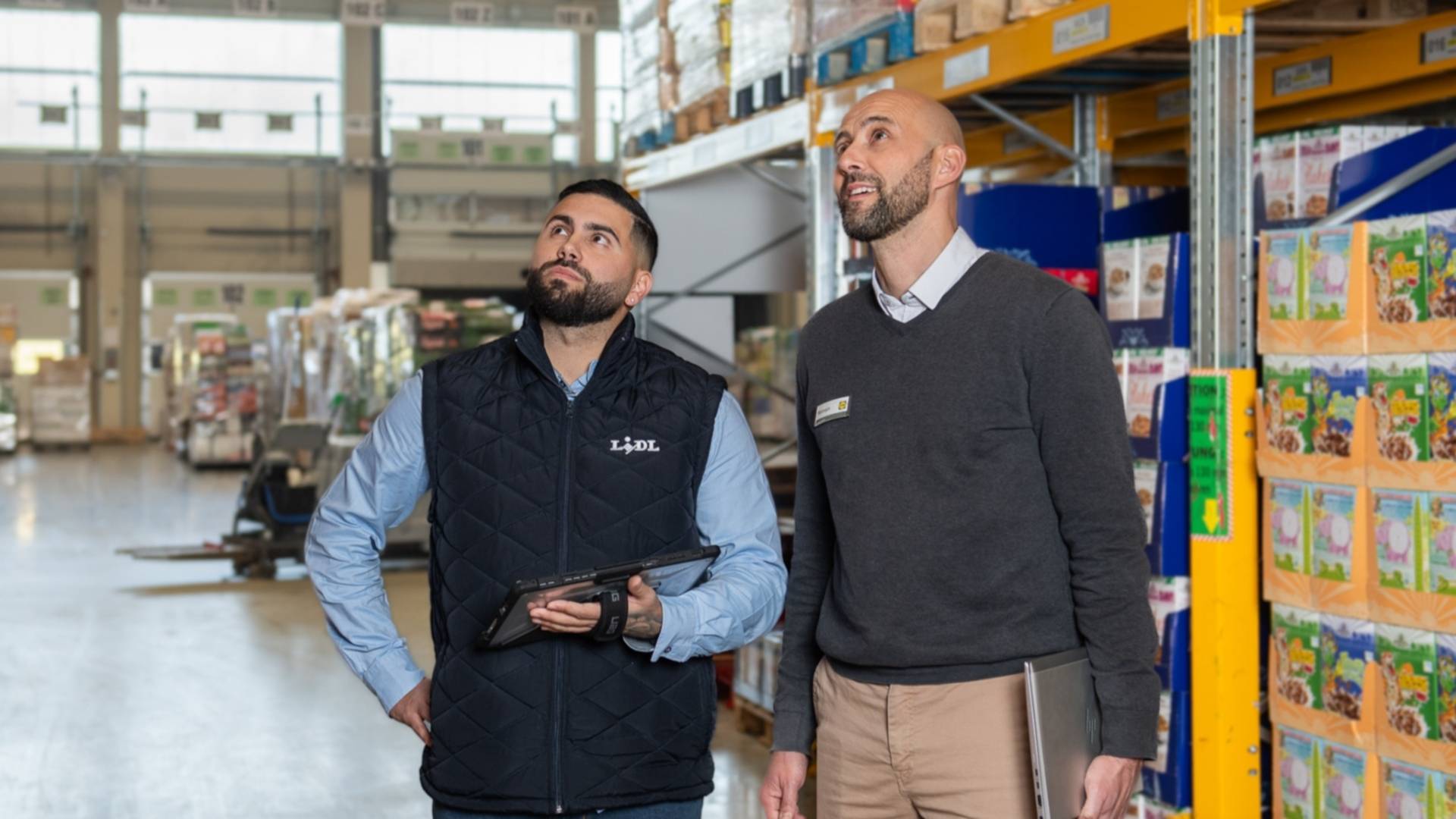 Un Responsable de Plateforme Logistique inspecte les allées de produits avec son Adjoint
