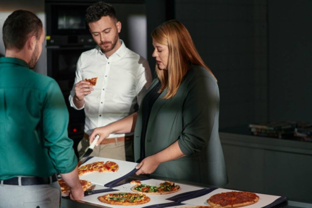 Un groupe de collaborateurs Achats sont autour d'une table et opèrent un contrôle qualité sur une gamme de pizzas surgelés