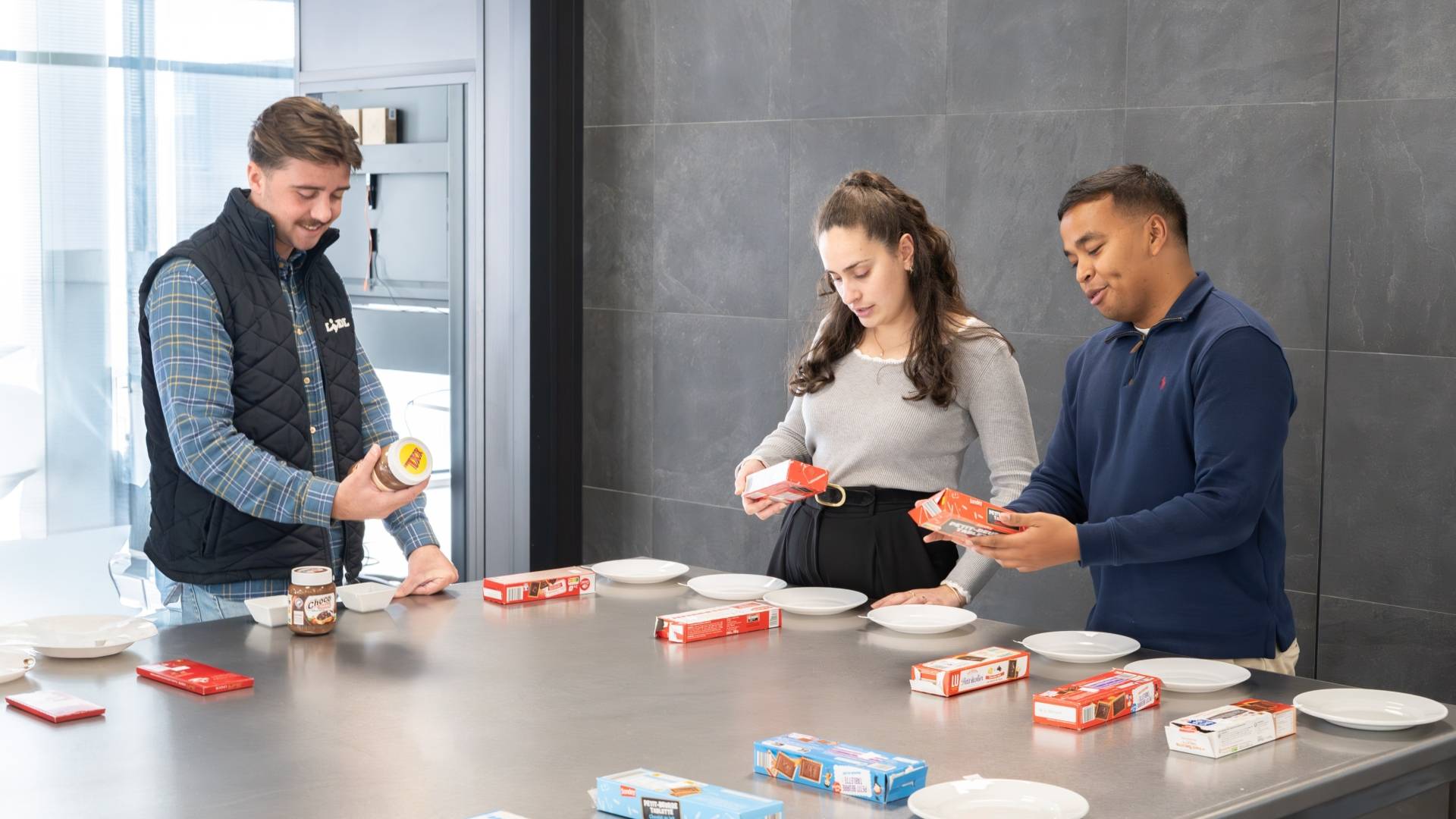 Un groupe de collaborateurs Achats sont autour d'une table et opèrent un contrôle qualité sur une variété de biscuits chocolatés