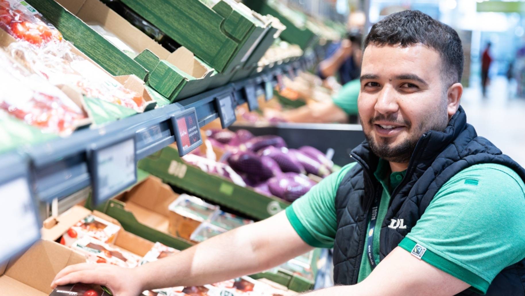 Jeune homme en train de travailler au rayon fruits & légumes