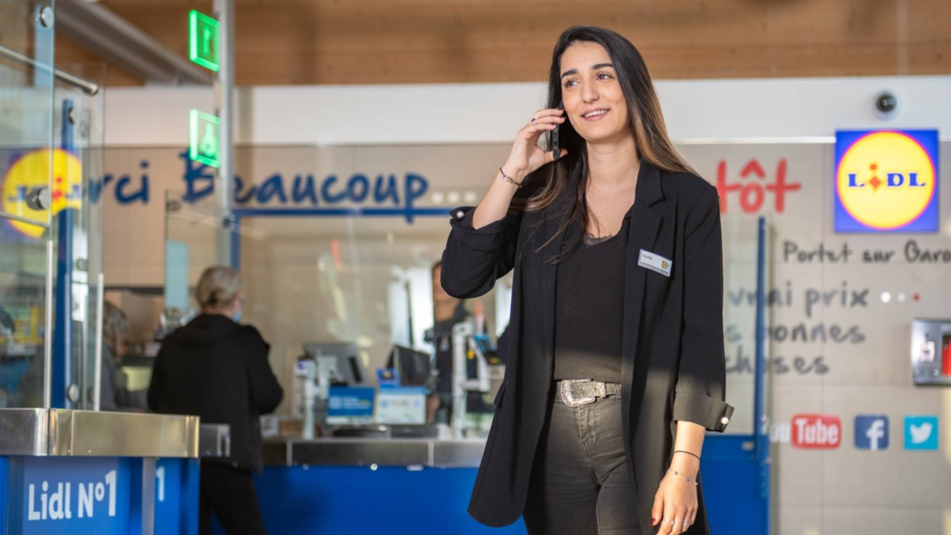 Jeune femme Responsable des Ventes Secteur répondant à un appel téléphonique dans un supermarché Lidl