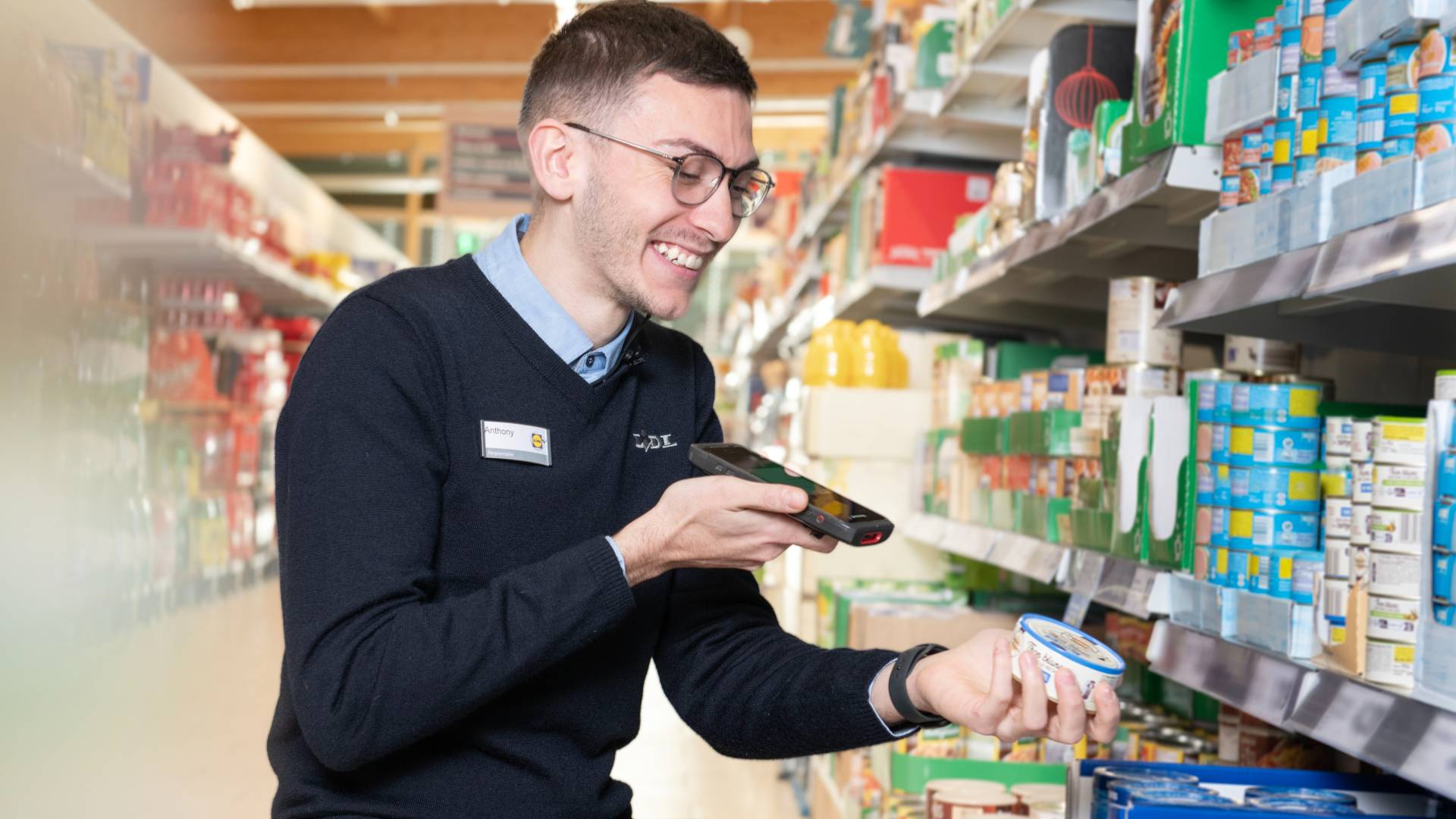 Jeune adjoint de supermarché en train de scanner un produit en rayon