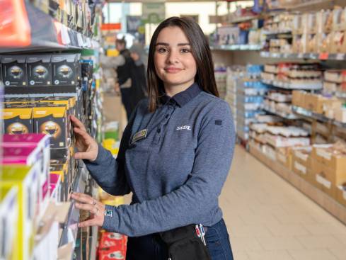 Jeune fille en polo de travail, dans les rayons d'un supermarché Lidl
