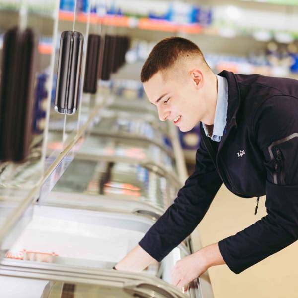 Un jeune équipier polyvalent qui vérifié les produits surgelés en supermarché