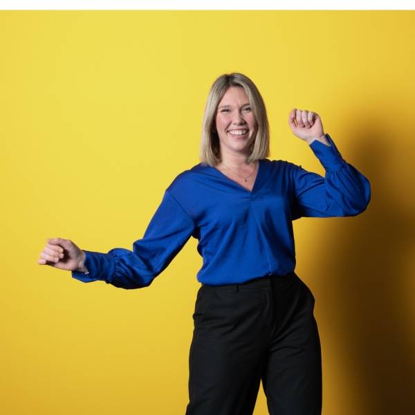 Jeune femme souriante en tee-shirt bleu sur fond jaune
