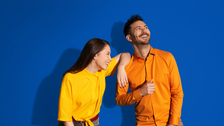 Deux jeunes femmes sourient à la caméra - celle de gauche porte un pull bleu clair, celle de droite un pull rouge à boutons dorés